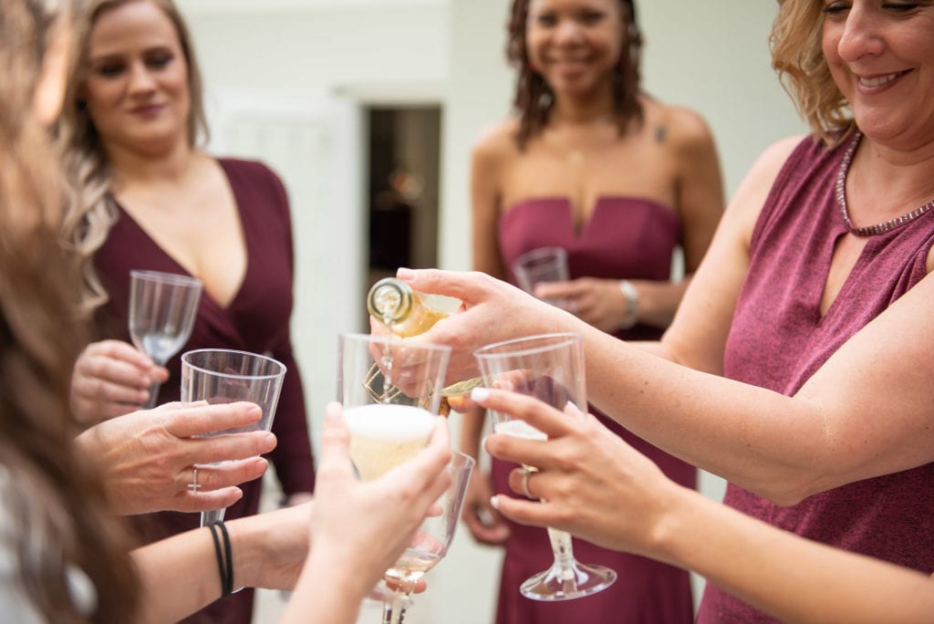 Ybor City Museum Garden Wedding Bride and Bridesmaids toasting with champagne wearing wine burgundy dresses close up