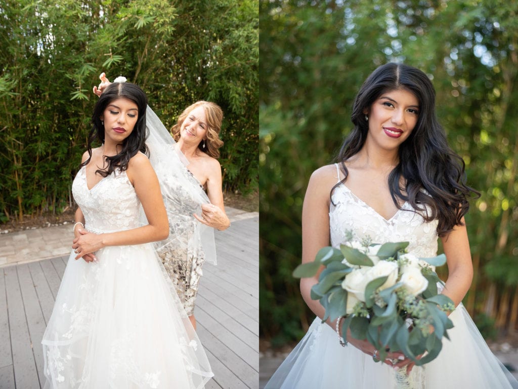 Ybor City Museum Garden Wedding Bride holding white flower and greenery bouquet smiling at camera bride and bride's mom fixing her veil