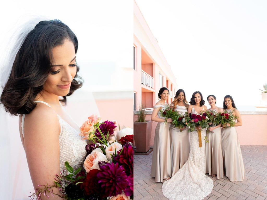Hyatt Regency Clearwater Beach Wedding Bride in Galia Lahav sexy sicilian wedding dress and bridesmaids in golden hollywood dresses holding bouquets in reds and pink colors looking at the camera smiling on the sky terrace of the hotel with water in the background
