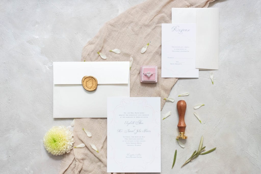 Basic Invite Luxury White and Peach Wedding Invitation Suite Flat lay photography with blush mrs ring box flowers wax seal and a styling mat