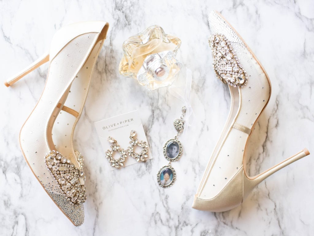 white and silver diamond wedding shoes perfume earrings and wedding accessories flat lay photography