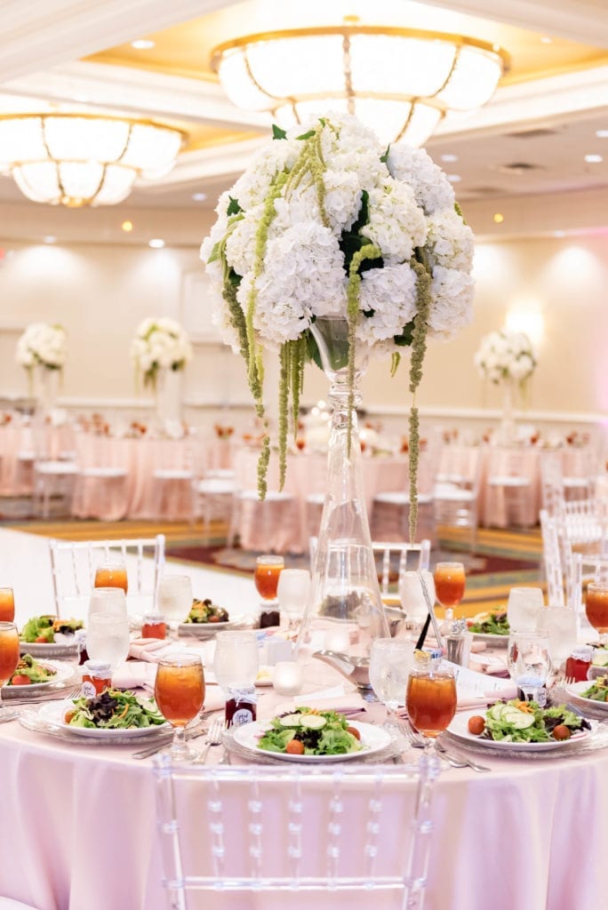 marriott grand ballroom wedding in tampa airport decor in blush and silver reception tables clear chairs and vases with draping flowers in white