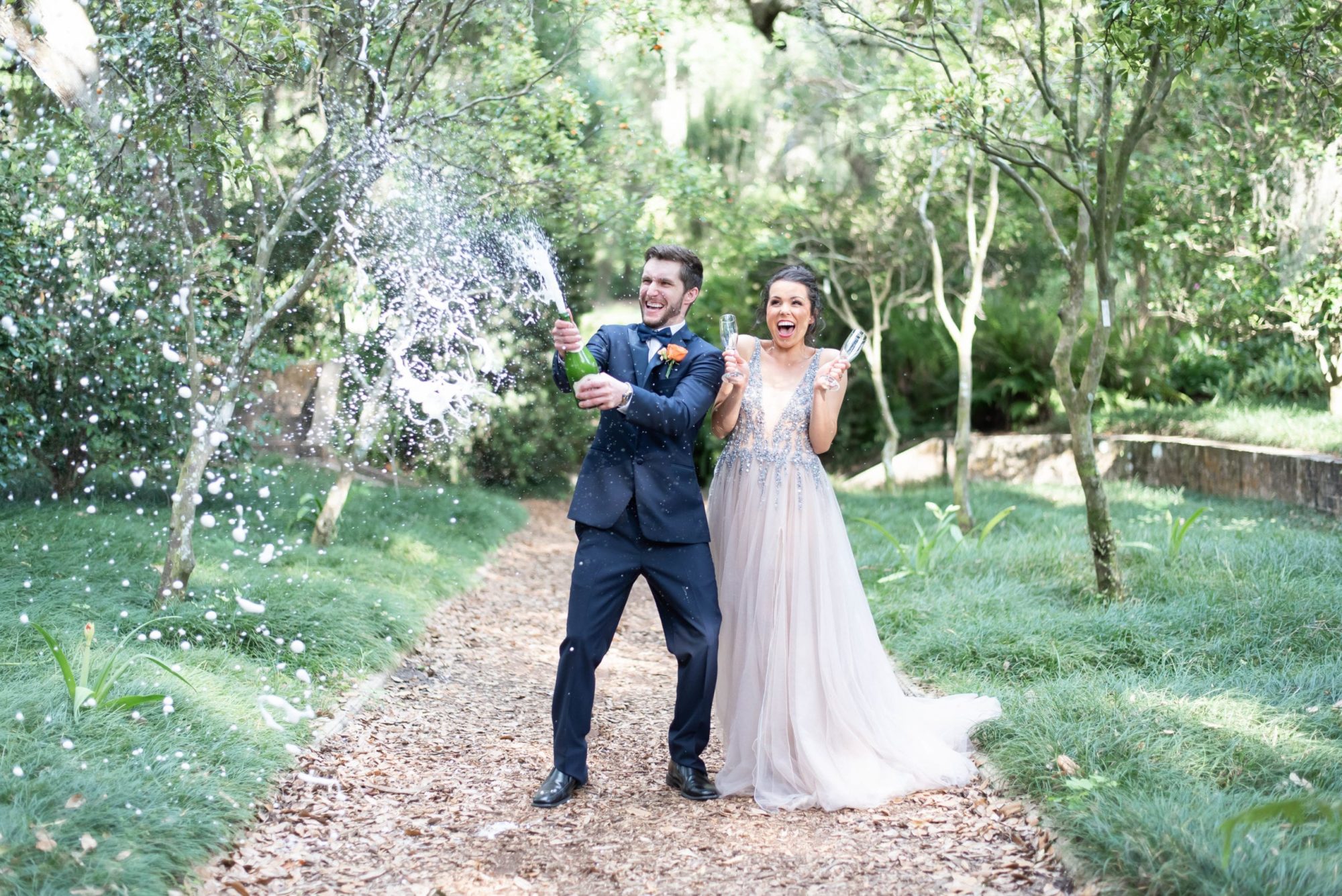 Bok tower garden wedding bride and groom pop the champagne photo in action capturing their reaction in orange grove garden