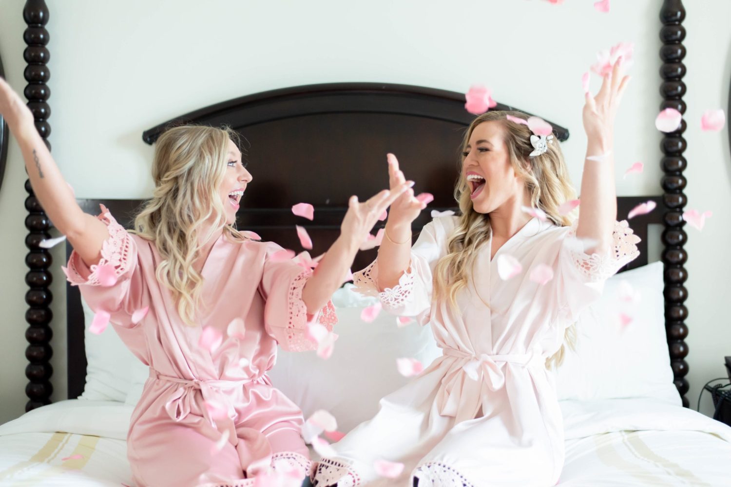 bride and maid of honor throwing flower petals on the wedding day at hotel room