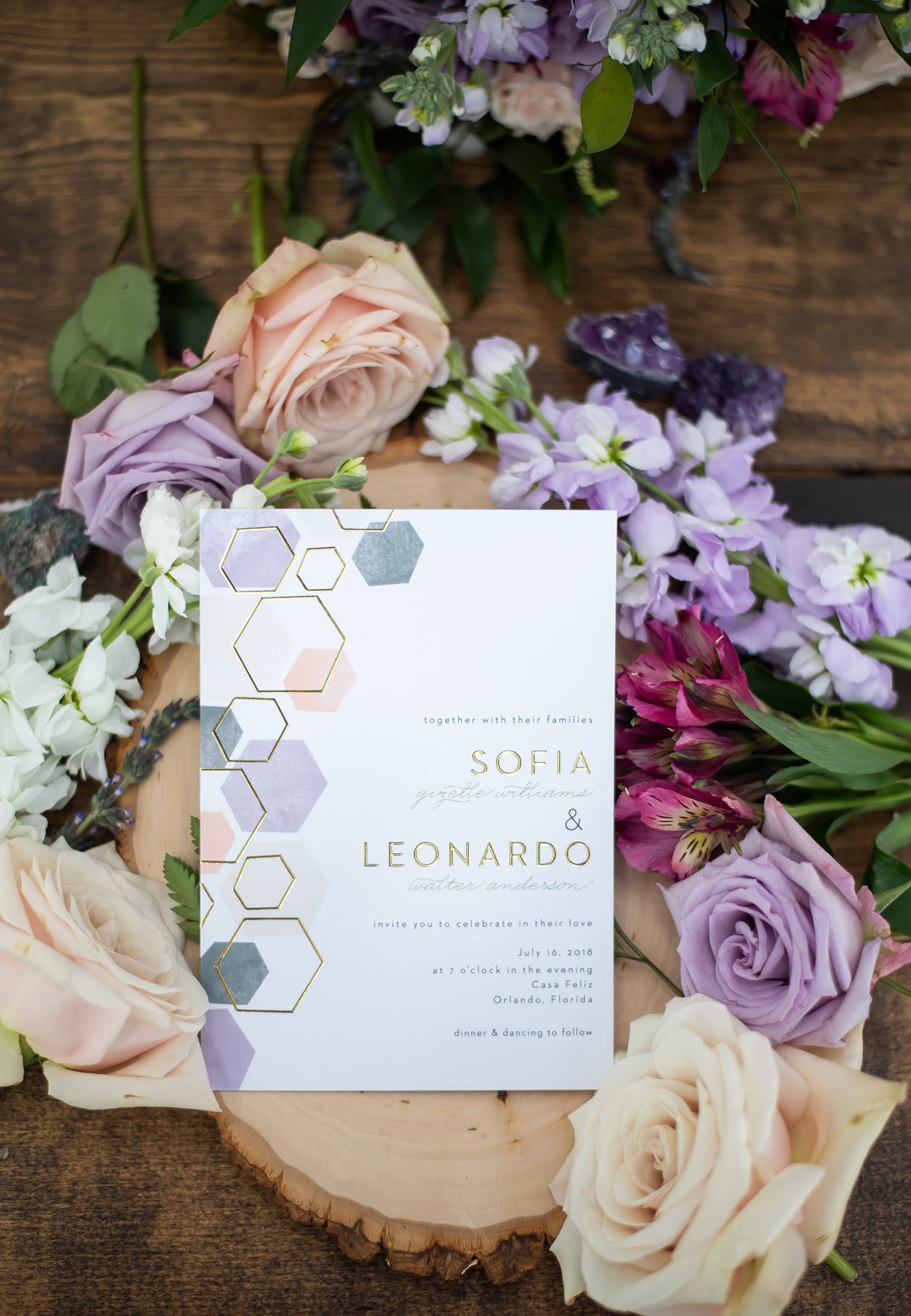 basic invite geometric invitation suite on wooden stand surrounded by roses