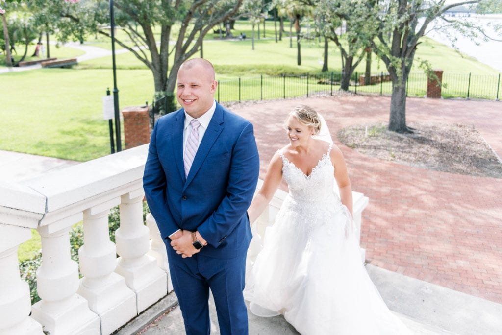 Downtown tampa first look bride in white dress coming up to groom in navy tuxedo grabbing his butt for first look at University of Tampa