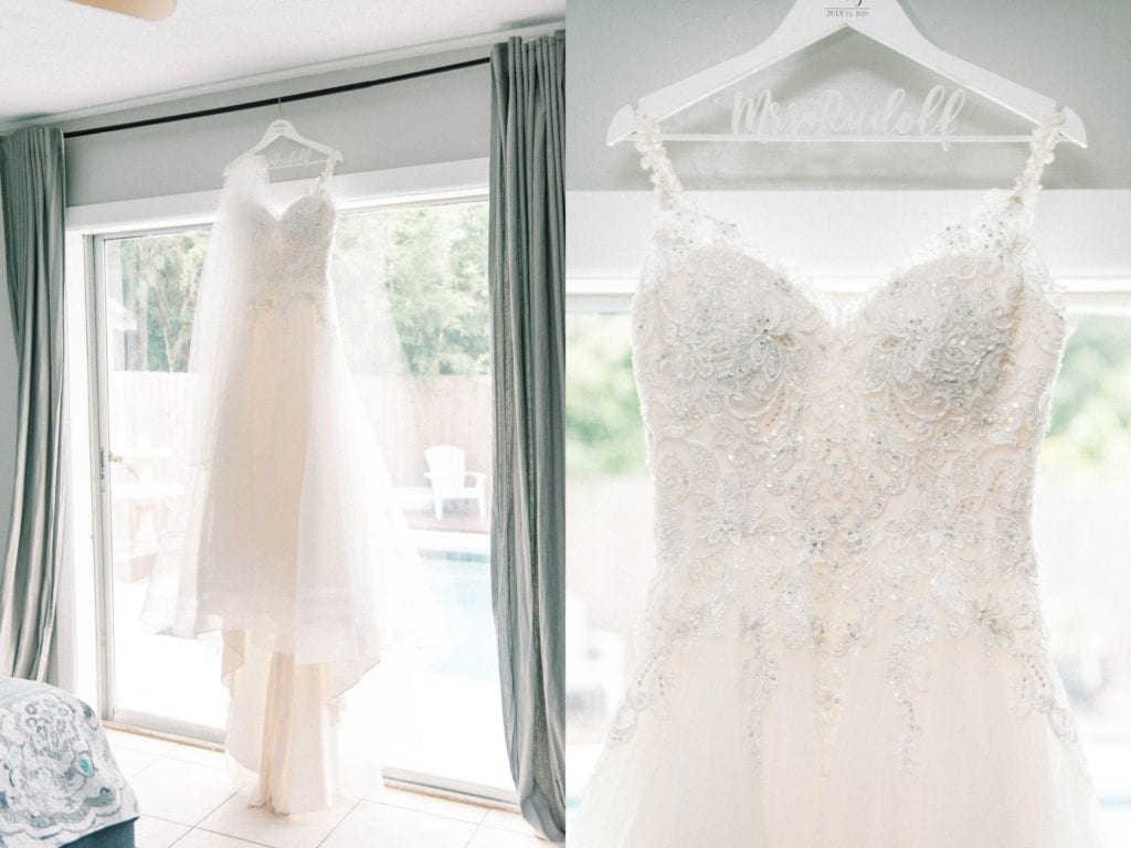 Sparkly champagne Rebecca Ingram wedding dress hung up by the window in a personalized wedding hanger 