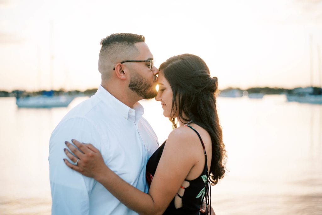Davis Island Sunset Engagement Photos Groom kissing bride's forehead at the beach at sunset