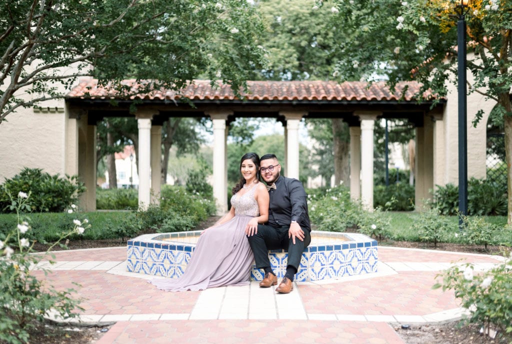 Rollins college engagement photos couple sitting down by fountain looking at the camera smiling