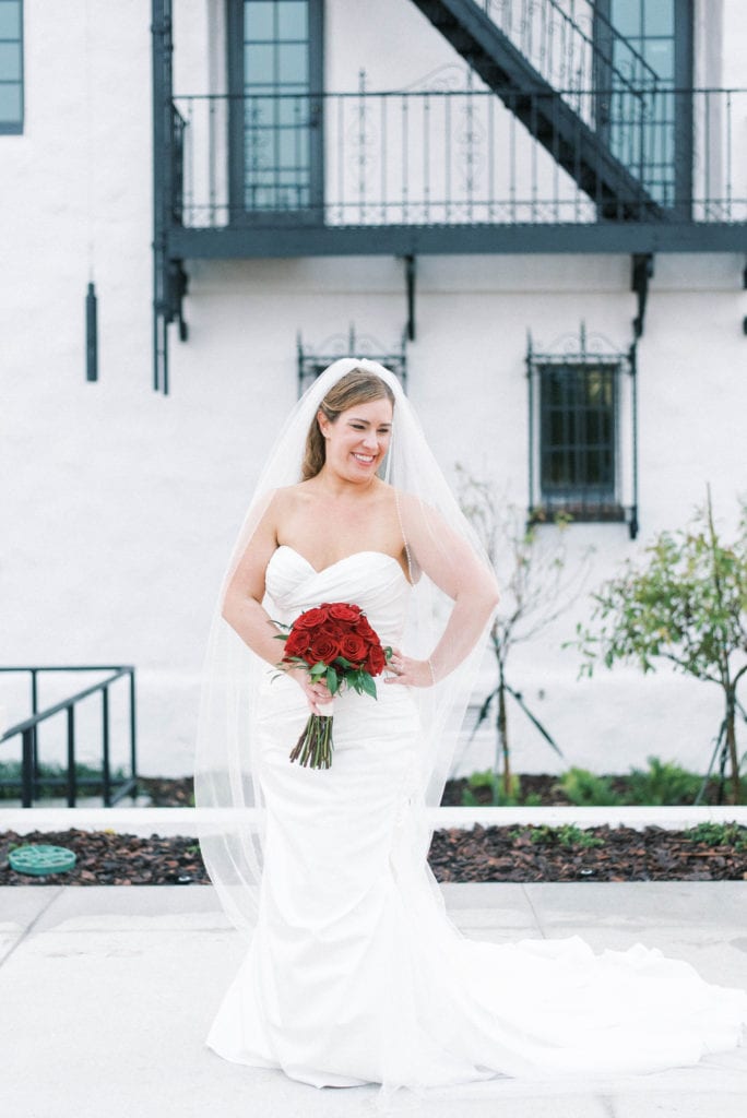 Bride posing with red rose bouquet of wedding flowers