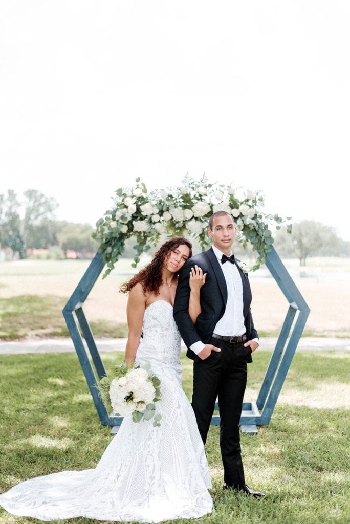Bride and groom portrait by blue wedding arch with white and greenery florals at orange tree citrus park in orlando florida