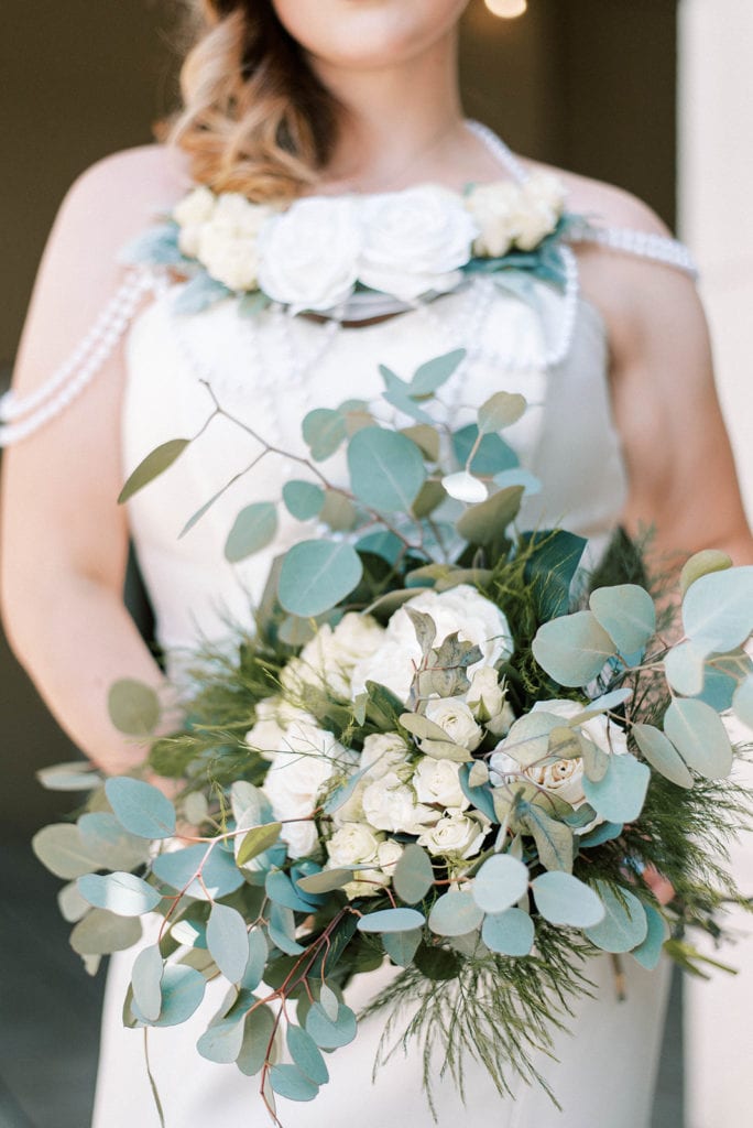 White and greenery wedding flower bouquet bride holding wedding bouquet and wearing flower necklace with pearls
