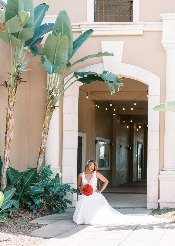 Falcons fire golf club wedding bridal photo by the palm tree florida bride wearing white dress and red floral bouquet