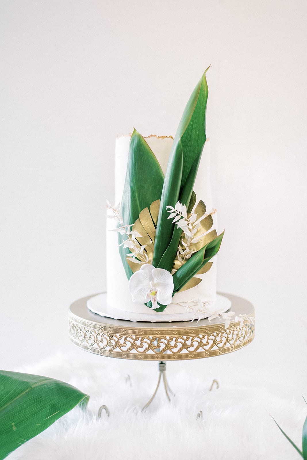 Top Reasons To Hire A Wedding Planner with White and greenery wedding cake with gold stand at falcons fire golf club simple and elegant wedding in orlando florida