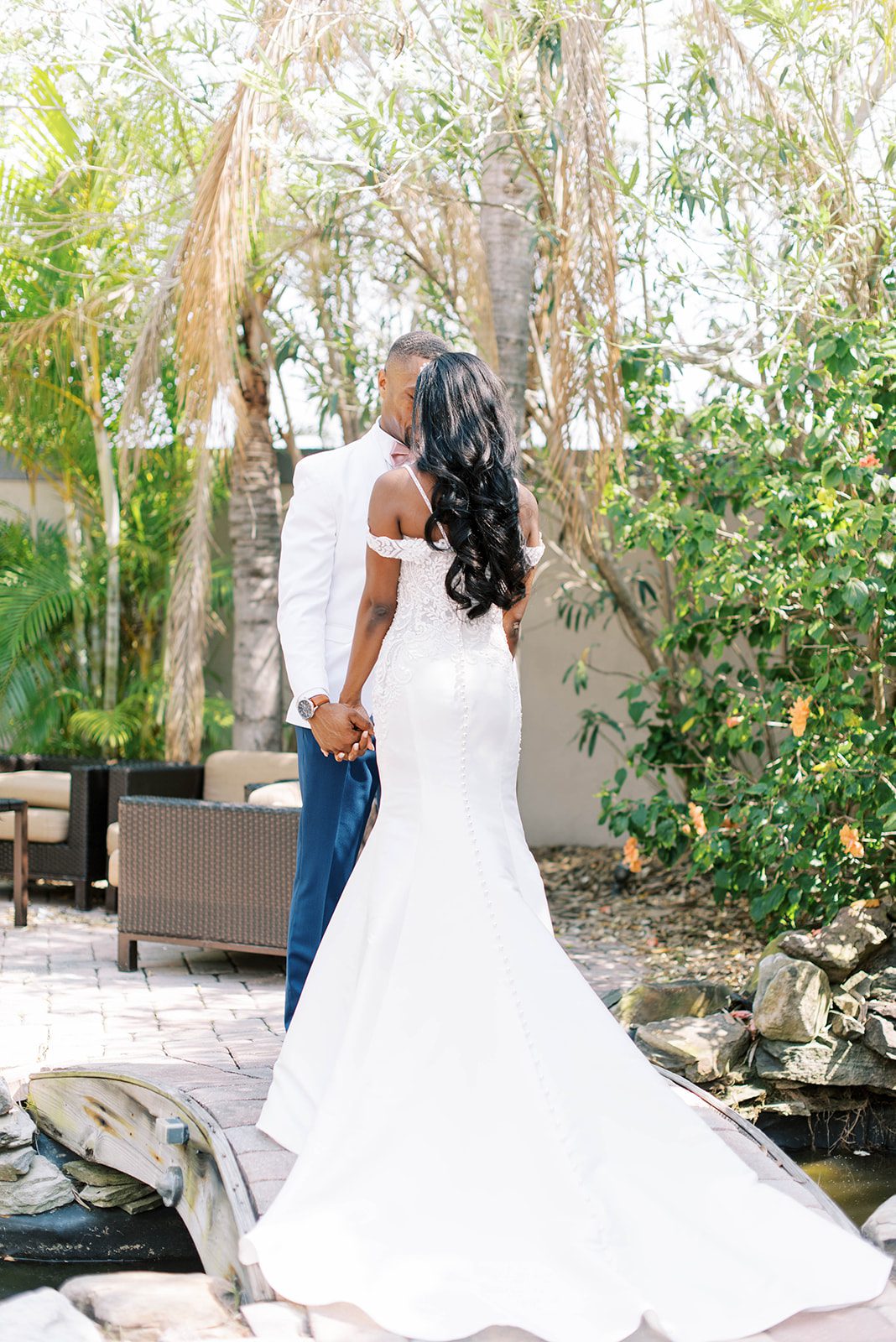 brides back is to the camera with her train extended while holding her grooms hands and kissing his at their Tampa Florida Wedding at their Bayanihan Arts and Events Center wedding venue