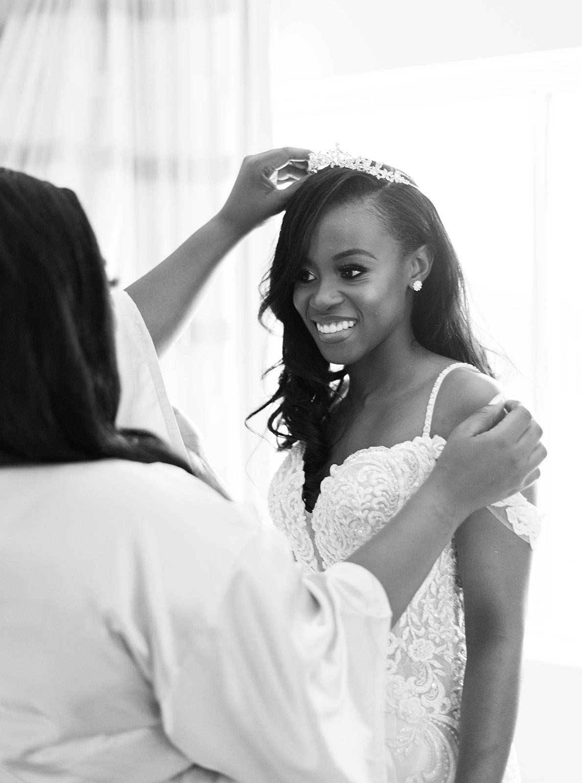 black and white photo of bridesmaid helping the bride adjust her tiara