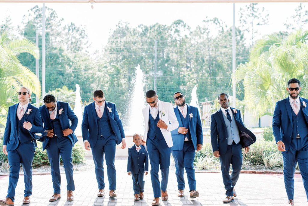 Groom and groomsmen posing for photos wearing navy tuxedos 