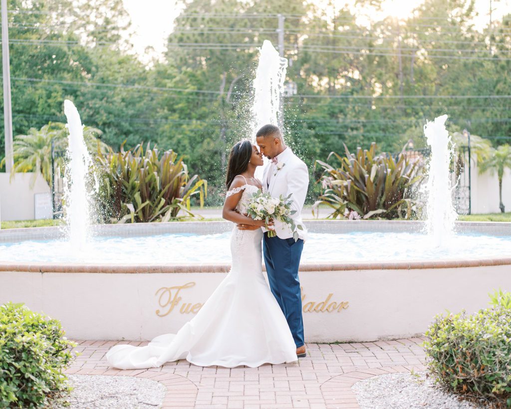 bride and groom standing in front of a fountain embracing each other and looking into each others eyes for their Florida Wedding