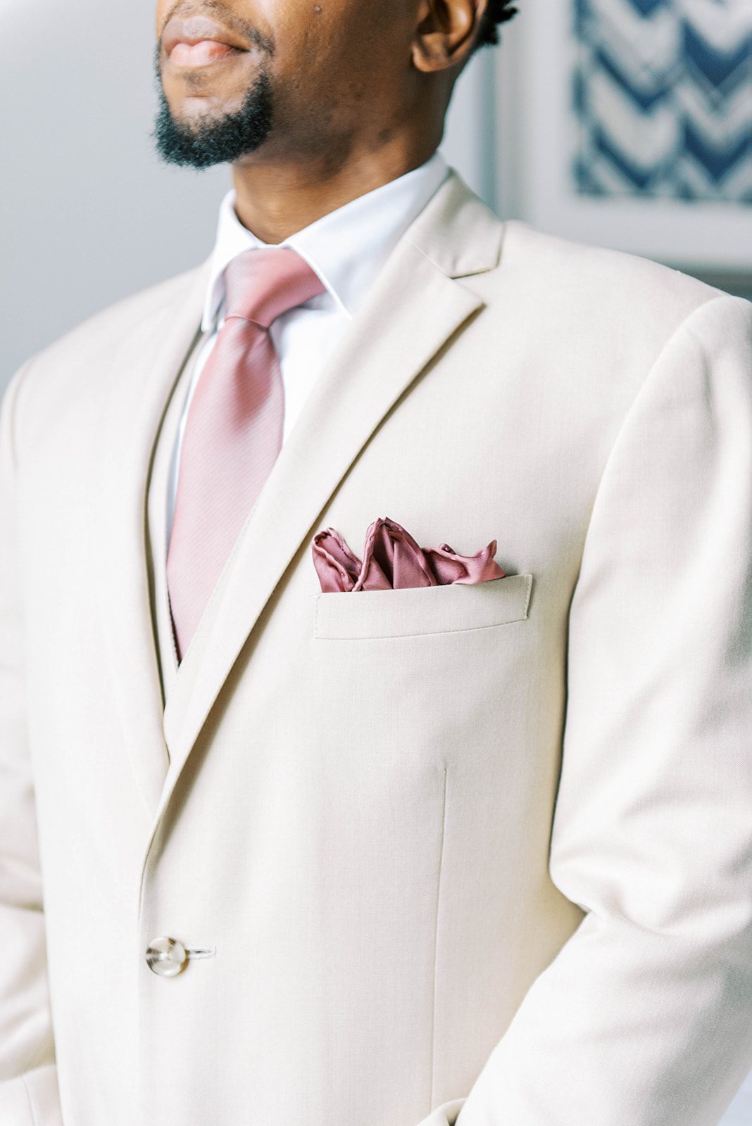 detail shot of grooms light cream suit with pink tie and pocket square