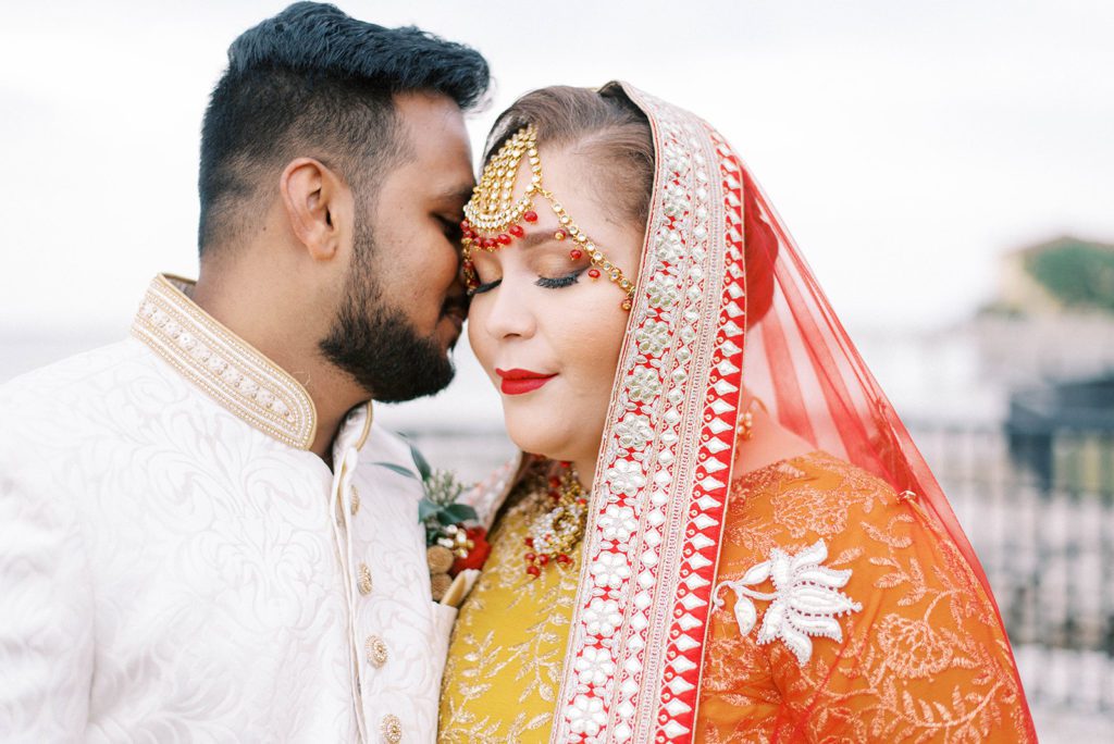 wedding planner puts together a wedding with an Indian wedding with man holding close his bride as she smiles while wearing her traditional wedding saree in Tampa Florida