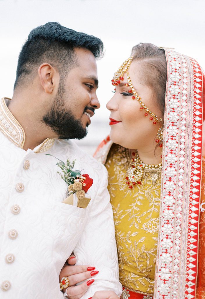 Indian bride holding her grooms arm and looking into his eyes as he goes in for a kiss at their Tampa Florida destination wedding