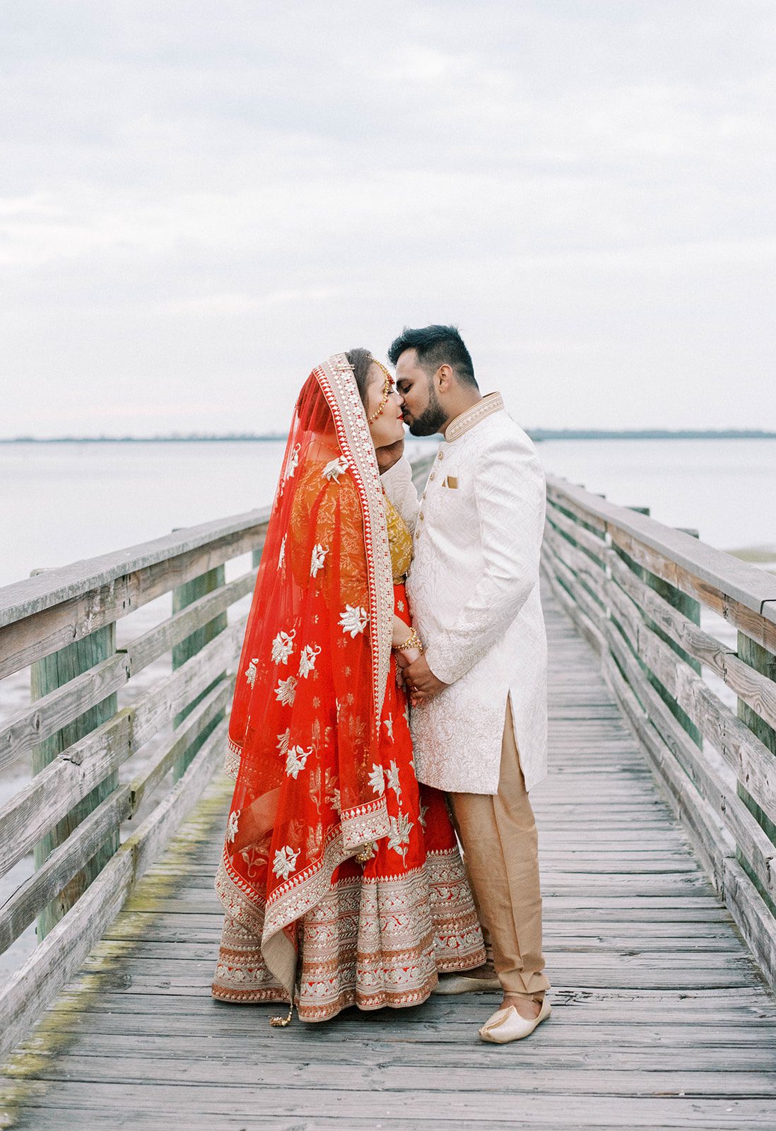 bride and groom standing on a dock in Tampa Florida and kissing during their Indian wedding