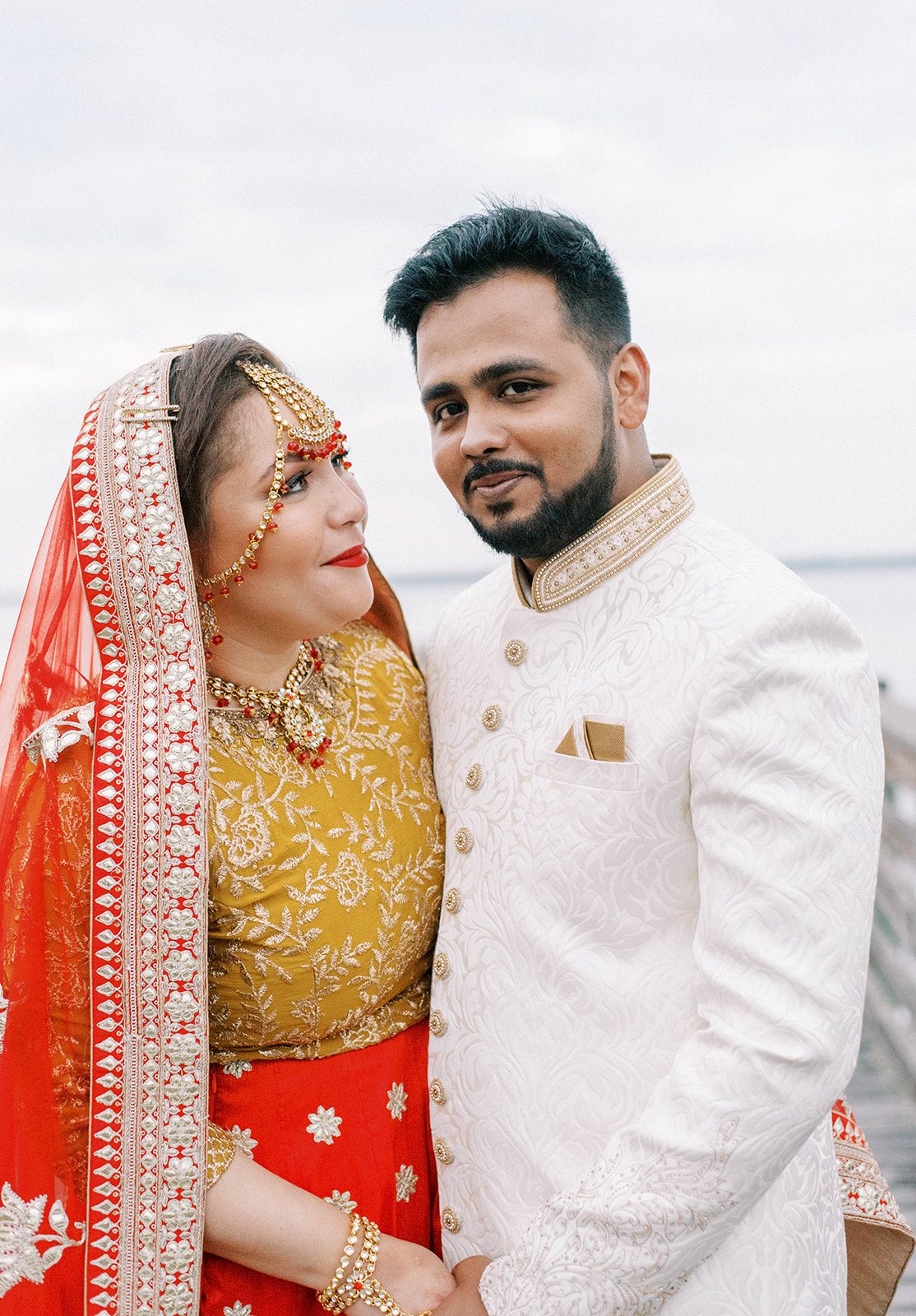 Indian bride and groom in traditional wedding attire standing on the ocean together for their Tampa Florida destination wedding