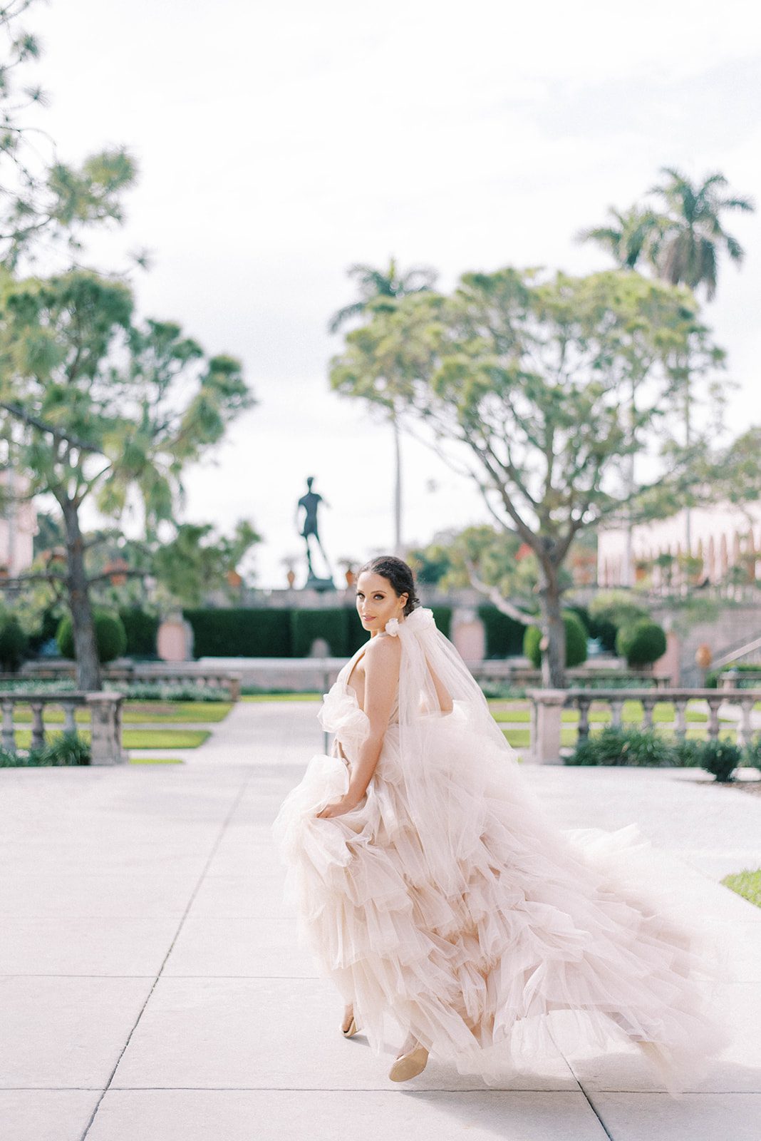 bride running across a courtyard in her ruffle and toule perfect wedding dress in Tampa Florida