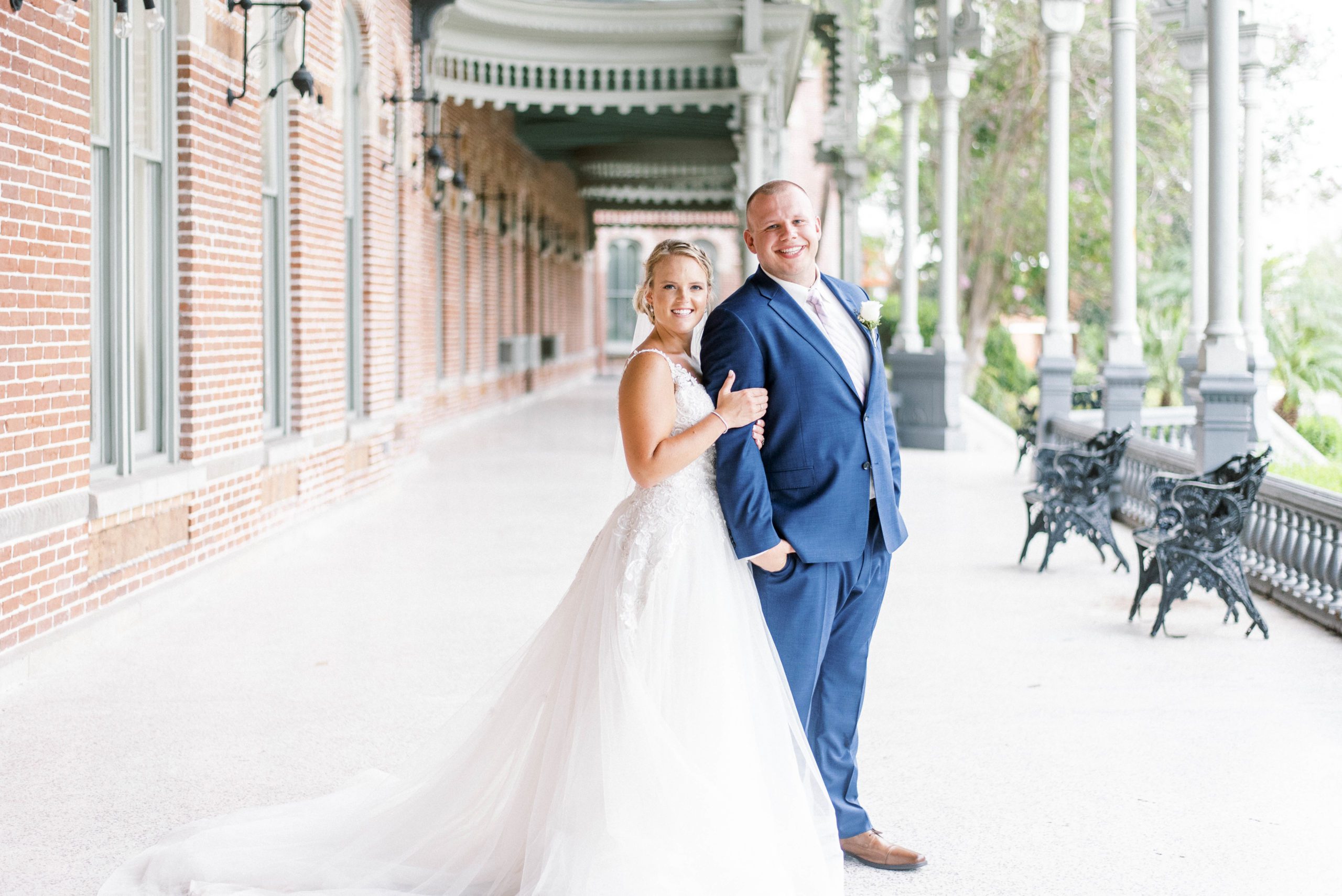 bride and groom standing on a large sidewalk near a dock in Tampa Bay for their bridal photos with best Tampa wedding photographer
