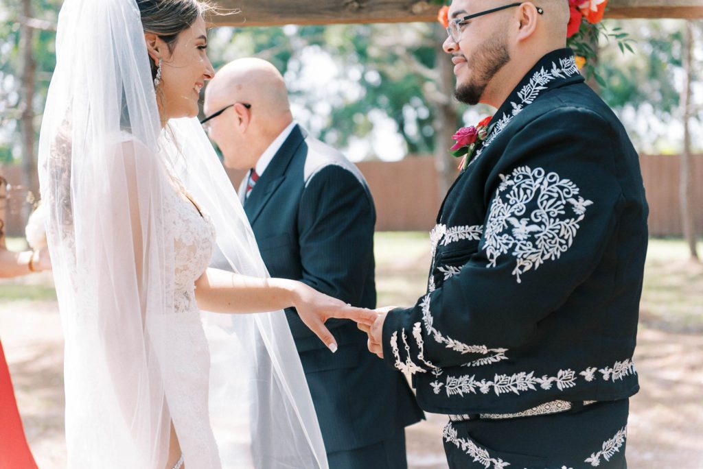 Wedding photography timeline sample and tips bride and groom during ceremony smiling at each other while groom wearing a mexican charro puts ring on her finger