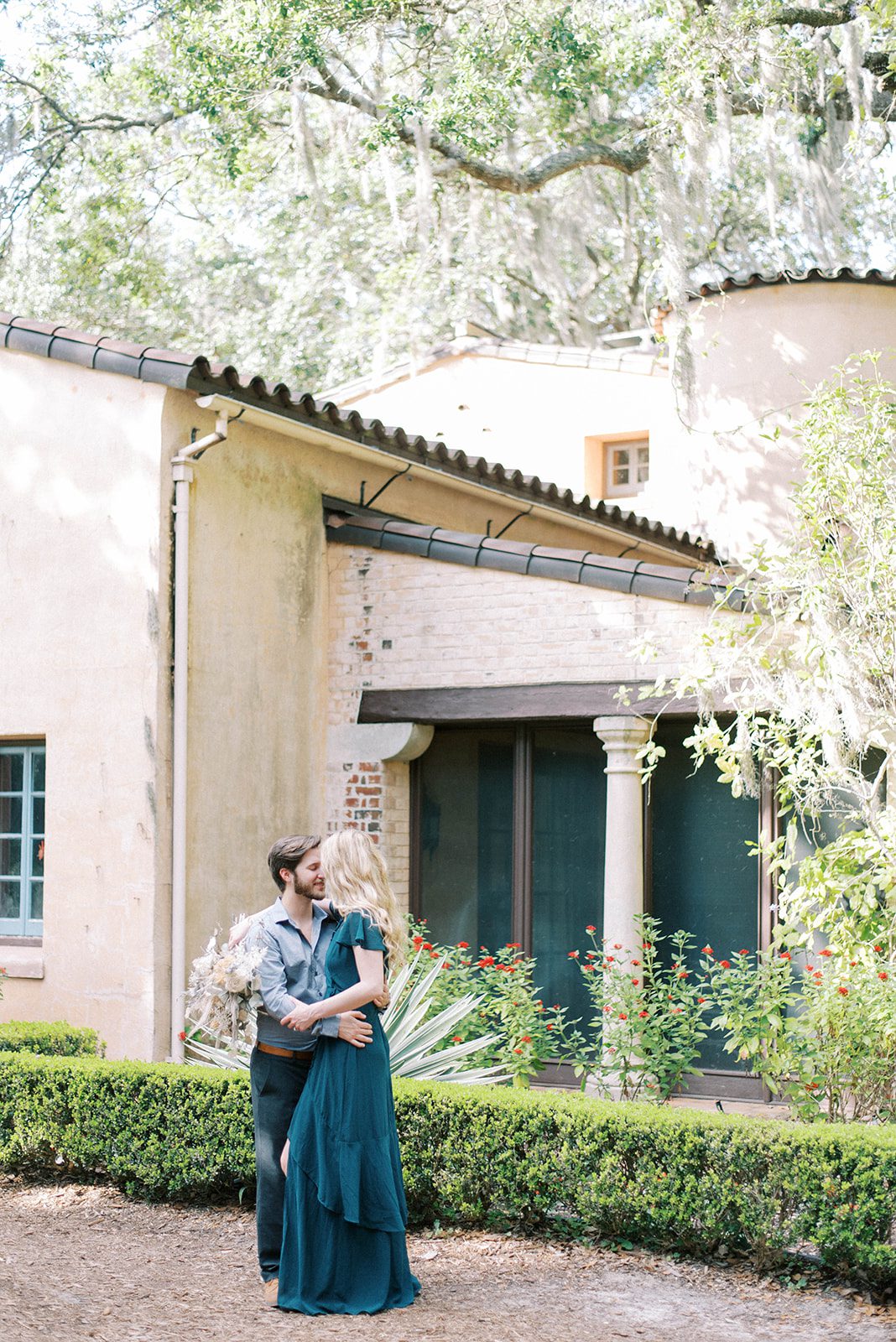 man and woman kissing next to an old spanish home in Tampa florida for their Engagement session