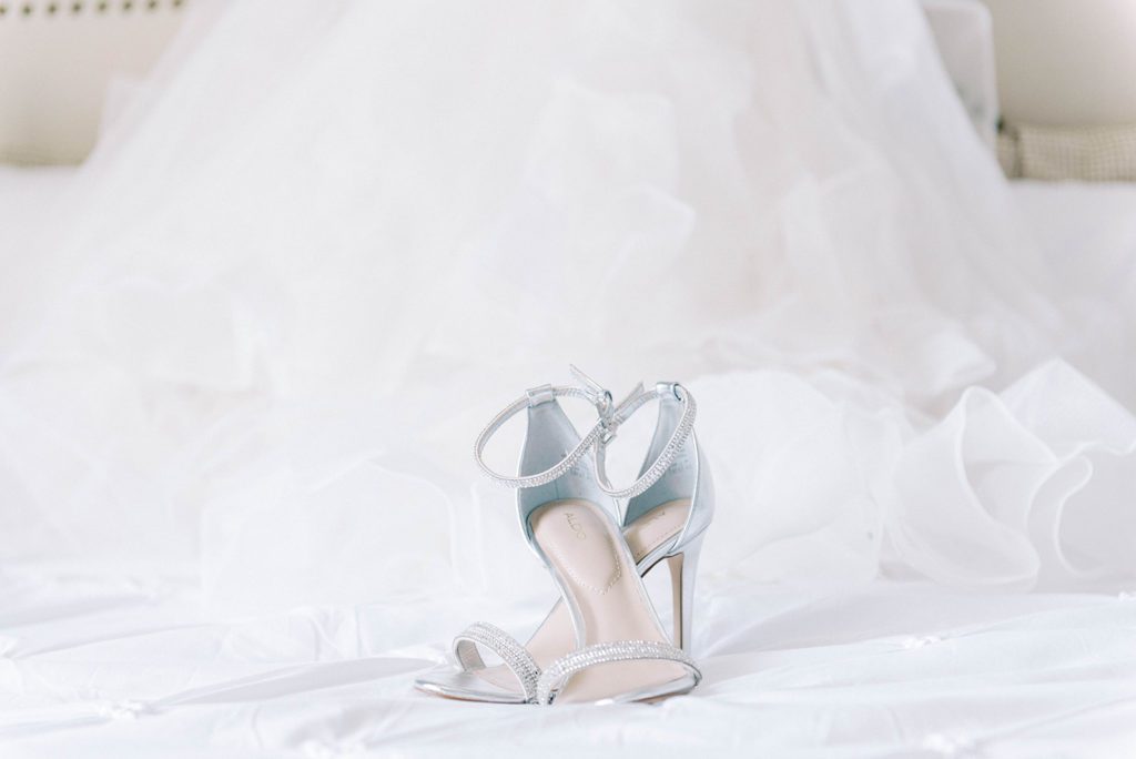 Micro Wedding in airbnb in tampa florida bridal silver shoes on bed with wedding gown in the background
