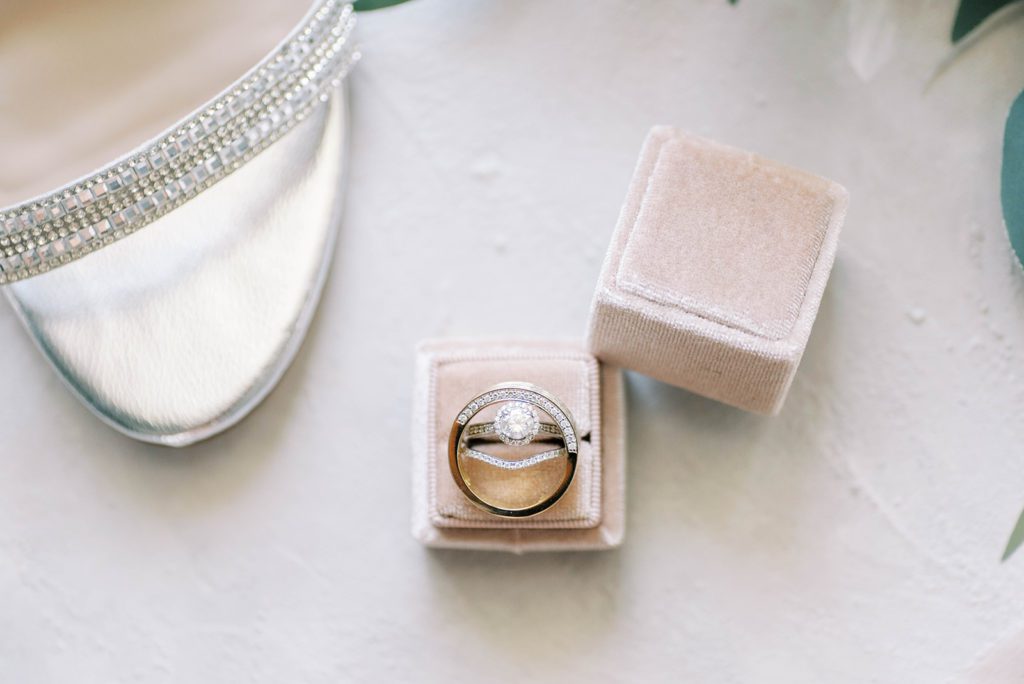 Wedding rings on pink mrs. box with silver bridal shoes flatlay