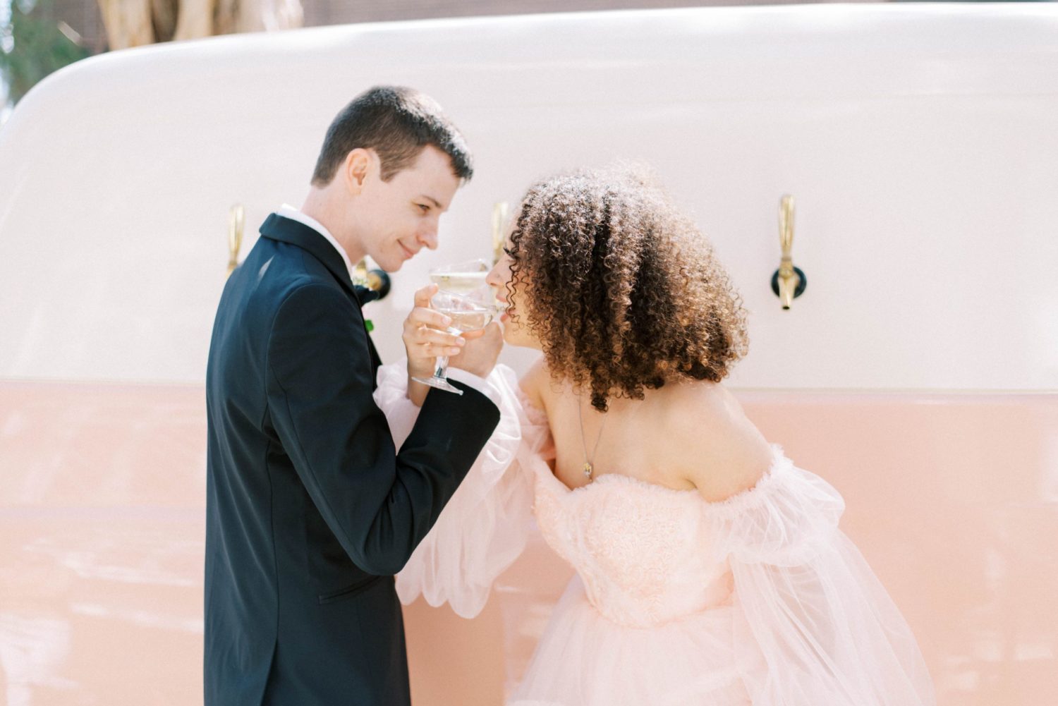 Wedding Photography Timeline Tips to ensure nothing gets missed bride and groom drinking champagne by bar smiling at each other groom wearing black tuxedo and bride wearing pink wedding gown