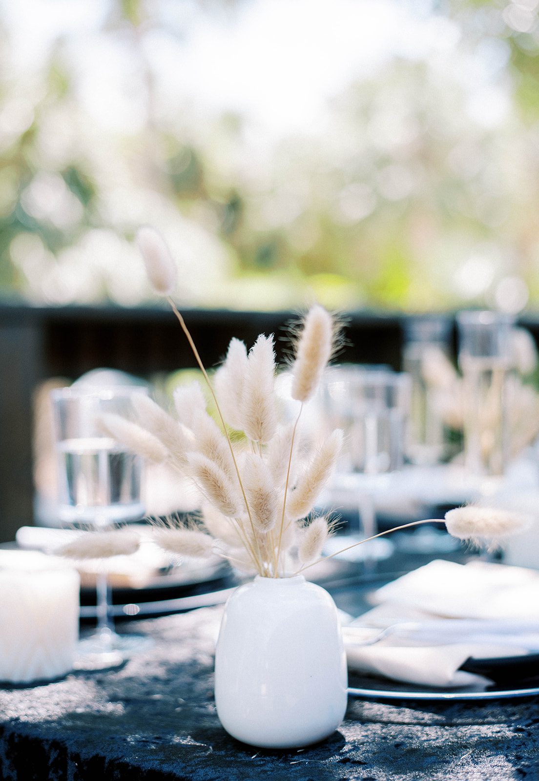 minimalist wedding at the Grand Ol' Barn in Florida with a dark table setting and white vases with mini pompous grass