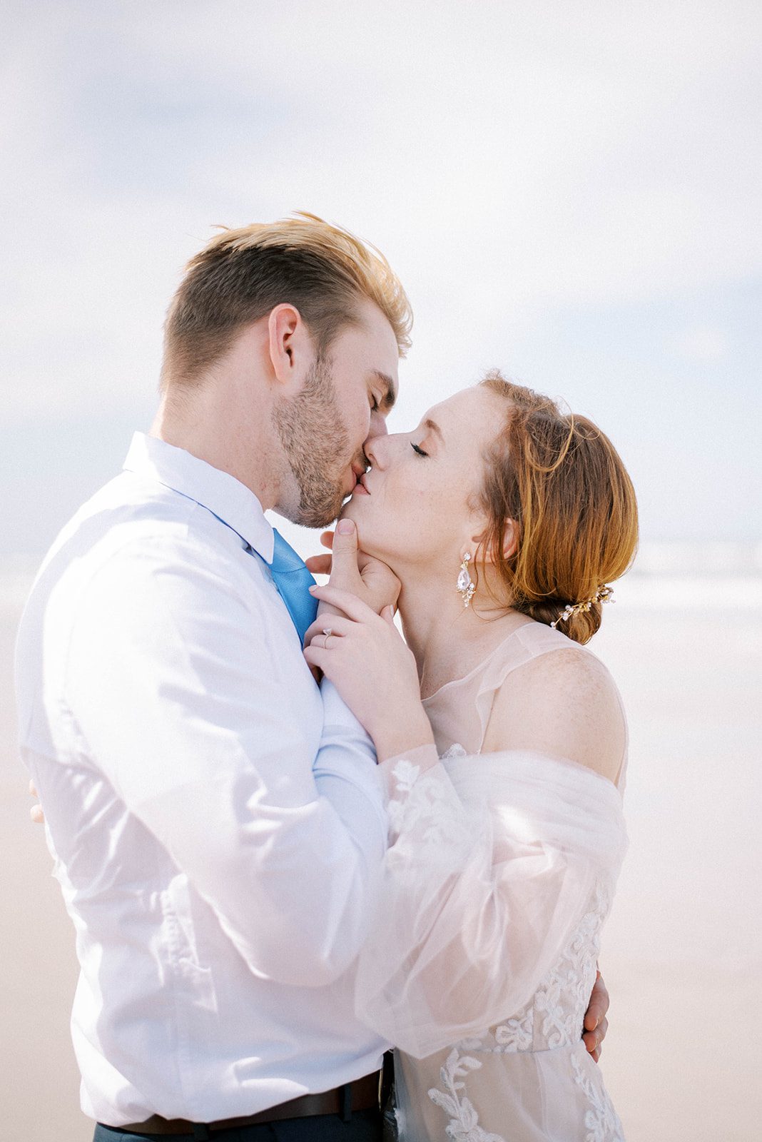 Florida beach wedding with bride and groom kissing each other passionately on the beach while the re head bride wears a lave and tulle gown and the groom is in a white shirt