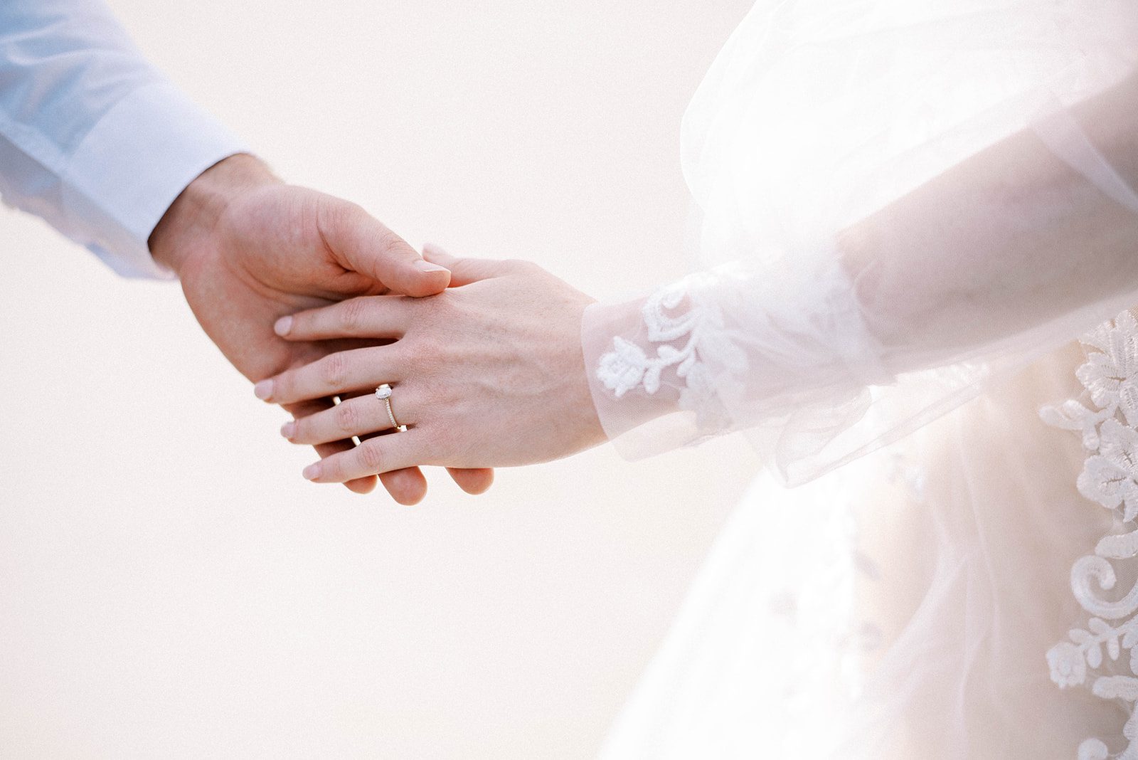 detail shot of bride gently holding her grooms hand while showing off her engagement ring and wedding ring at New Smyrna Beach for her FLorida beach wedding day