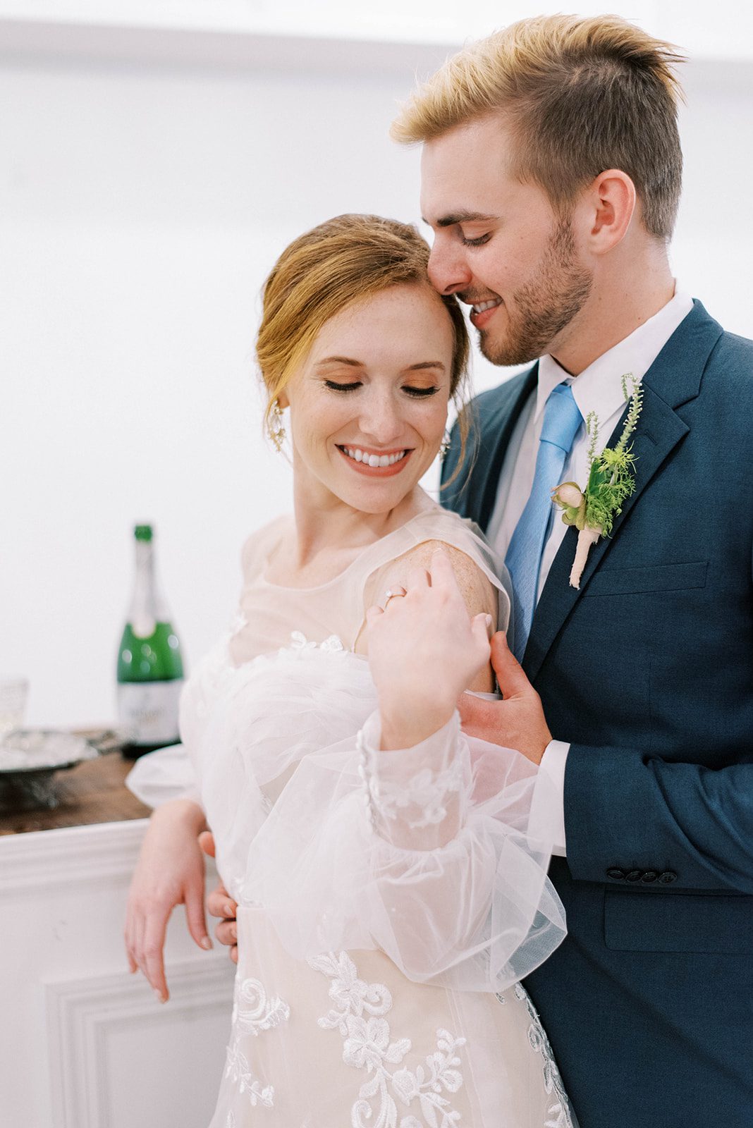 New Smyrna Beach wedding bride and groom on their wedding day with bride smiling down at her shoulder as groom stands behind her holds her arms with his nose touching her forehead ever so lightly