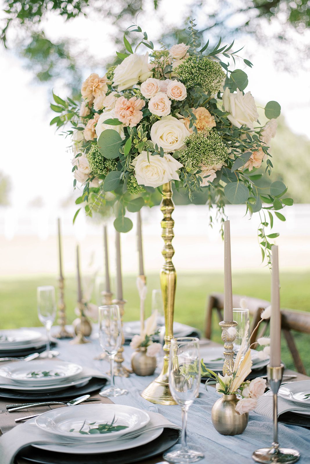 Top Reasons To Hire A Wedding Planner with Bridgerton inspired wedding with a tall gold stand holding a bouquet of rose and light greenery with candle sticks and other ornate glasses on the table