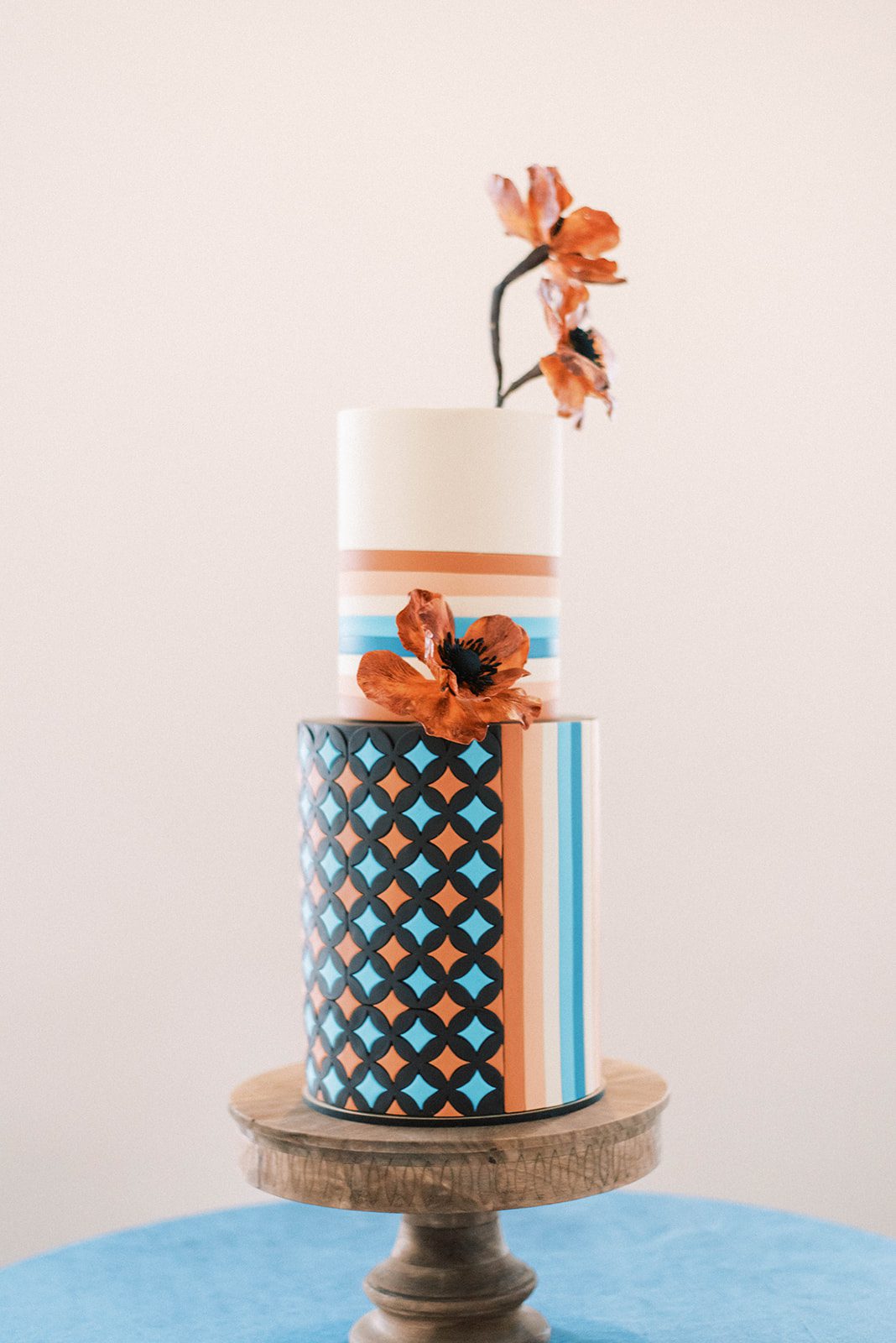 70s inspired burnt orange and blue wedding cake with flowers and diamond details
