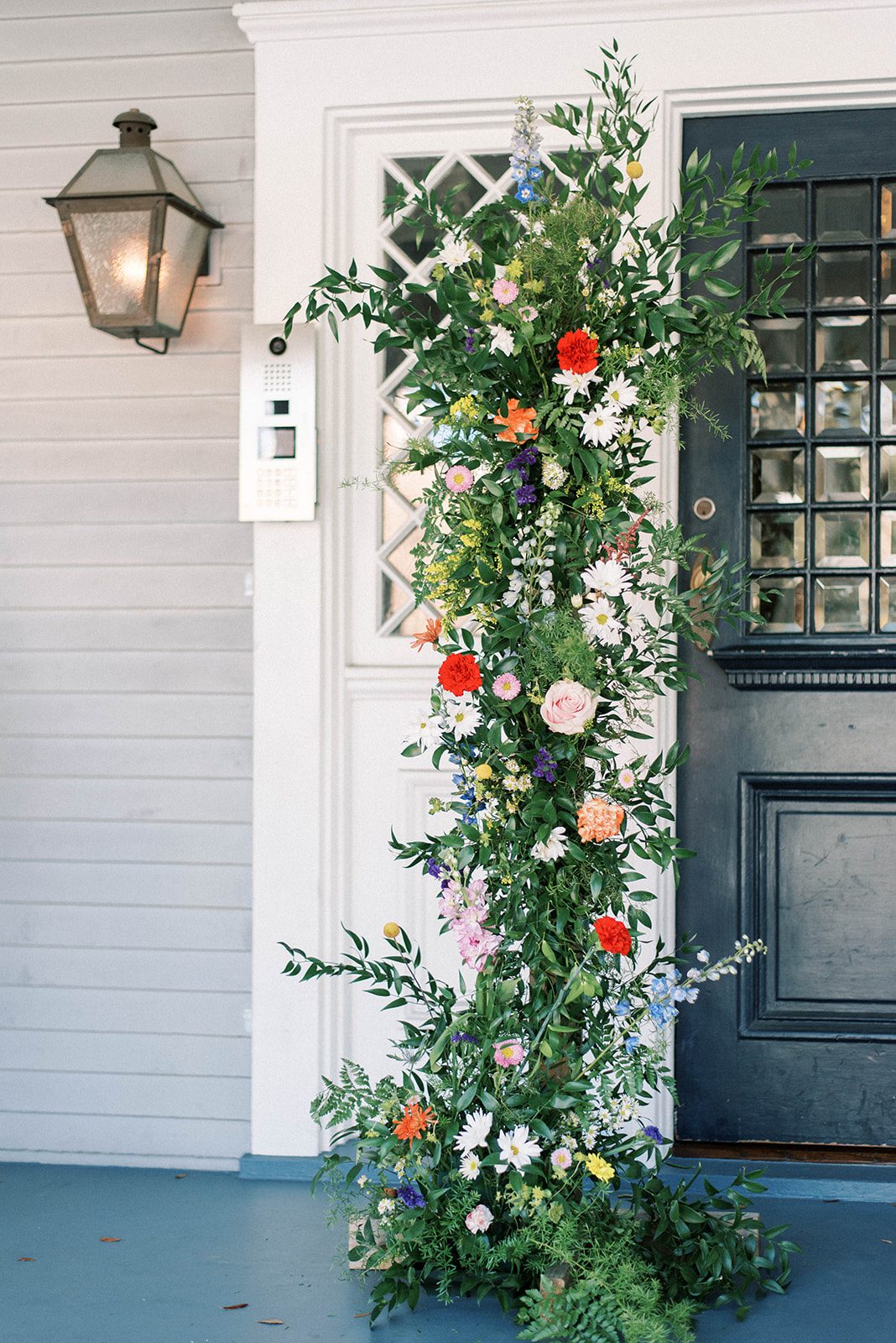 2022 Wedding Trends with Tall stand of bright green and colorful florals standing on the porch of The Orlo in Florida next to the door