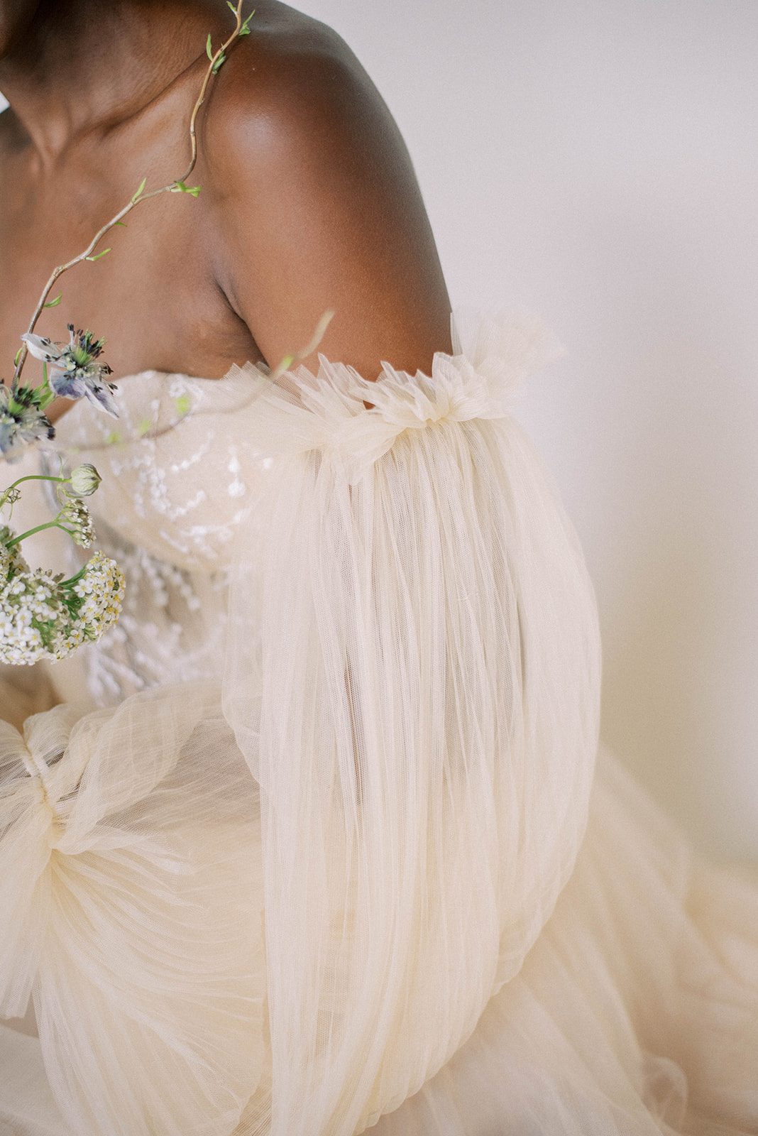 deatil shot of brides wedding dress with an off the shoulder sleeve in an off white gown