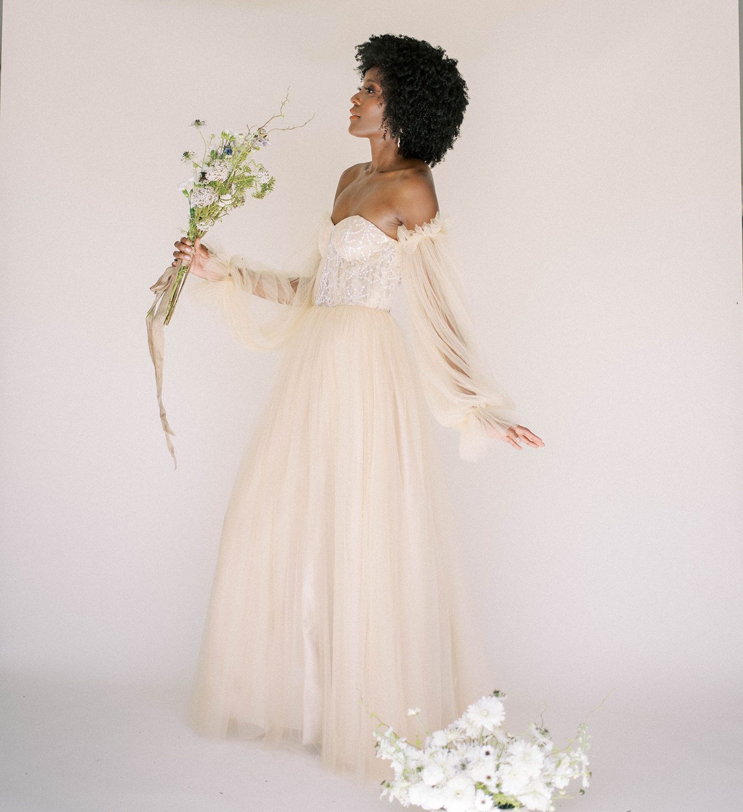 neutral bridal fashion, with bride in an off white gown holding a bouquet of wildflowers captured by Tampa Bay wedding photographers 