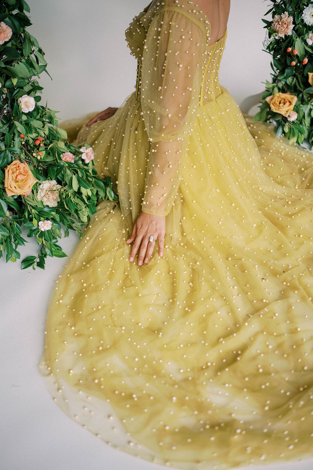 Tampa florida wedding photography with bride in a bright yellow wedding dress sitting on the floor of a studio with florals surrounding her
