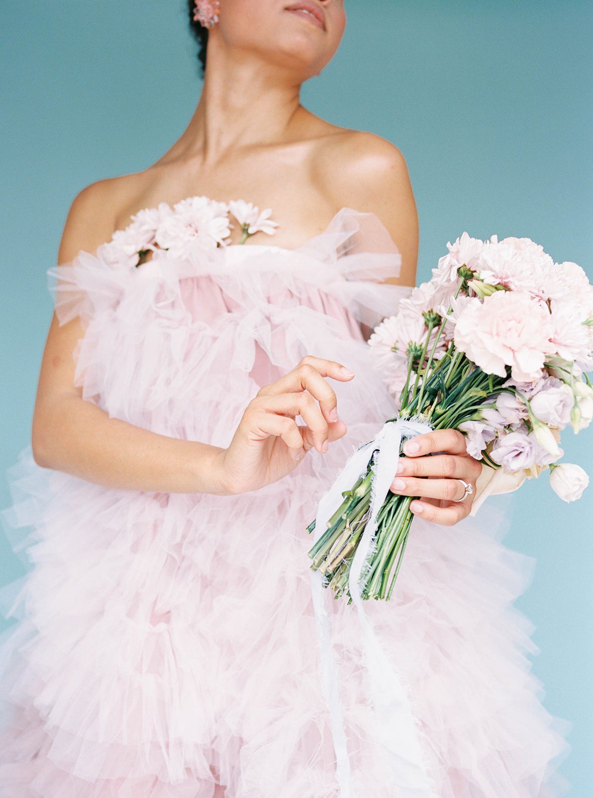 bride holding onto her floral pastel bouquet while wearing a lilac ruffled ballgown