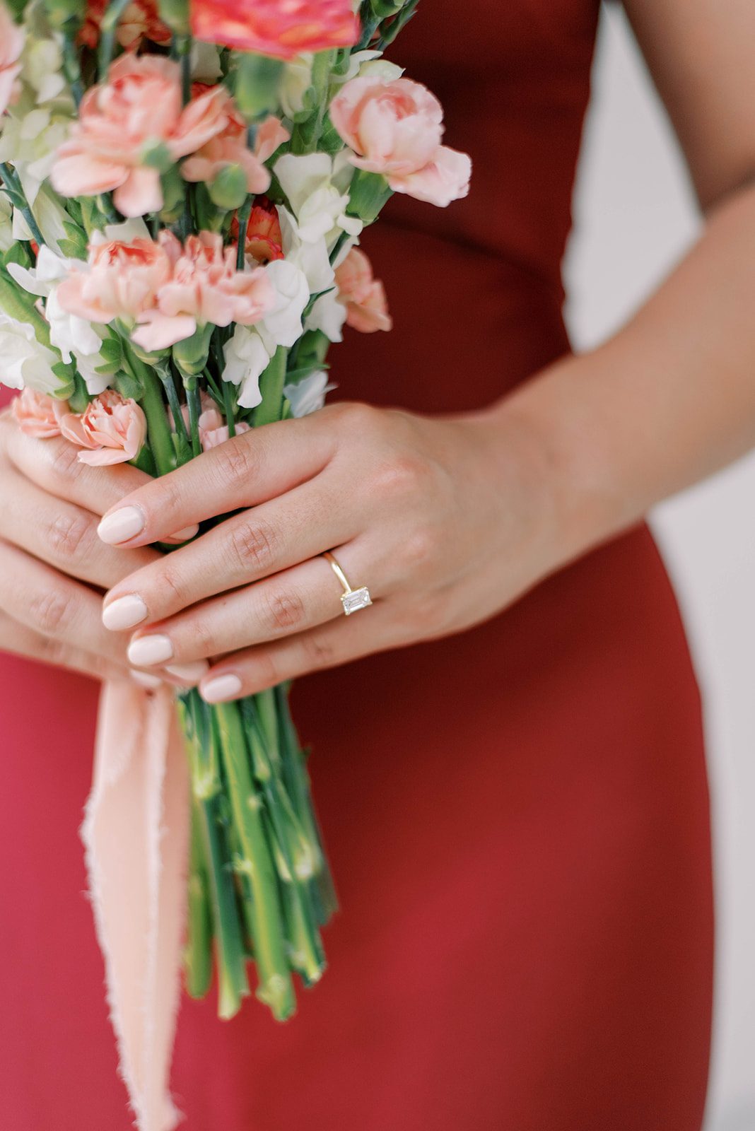 engagement photos with woman in red dress holding a bouquet of pink flowers and showing off her engagement ring