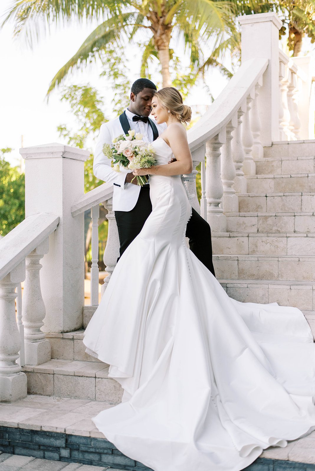 luxury wedding in Tampa Florida with bride and groom on the stairs of a castle and the groom leaning on the marble staircase holding his bride