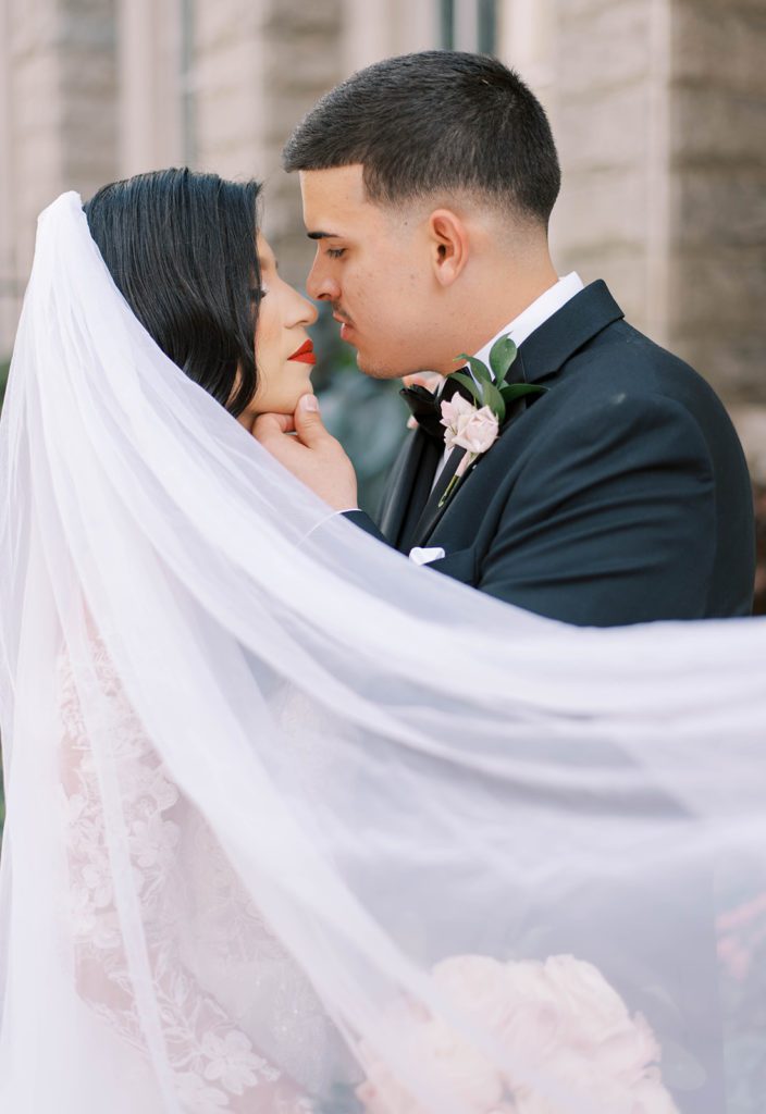 luxury wedding in Tampa Florida with groom caressing brides cheeks as her veil flows in the wind