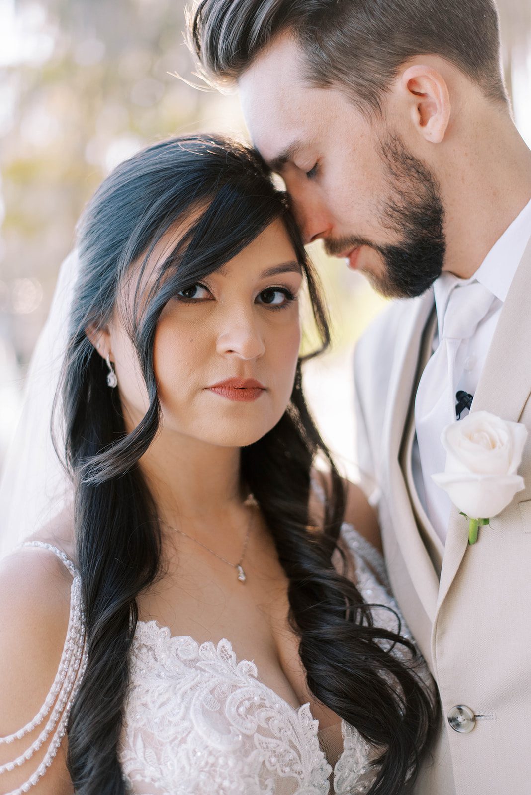 bride looking at the camera as her groom holds his head to the temple of her forehead and closes his eyes for their luxury Tampa Bay wedding