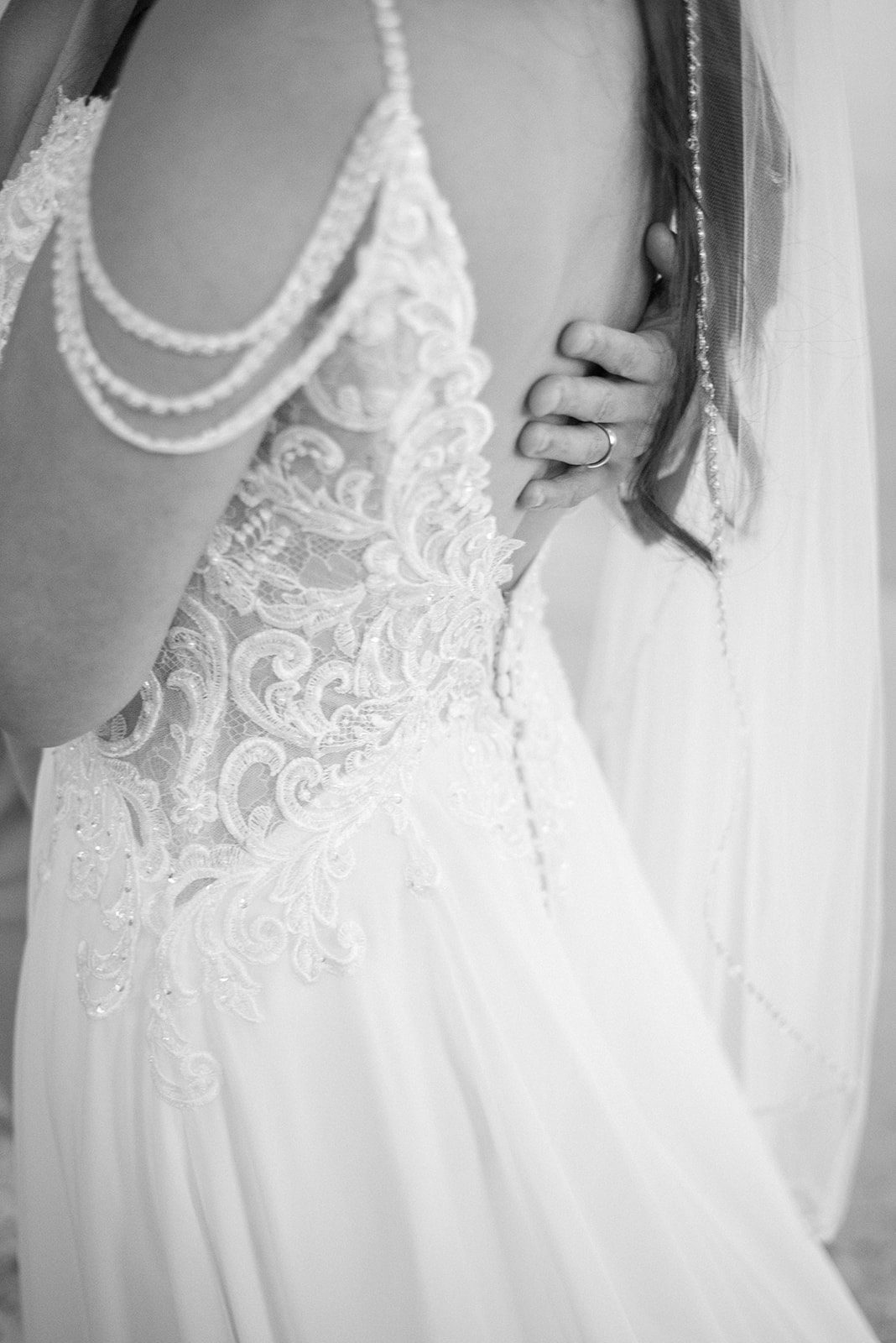 black and white image of a detail shot of the brides grown from the back with a lace bodice and beaded off the shoulder sleeve